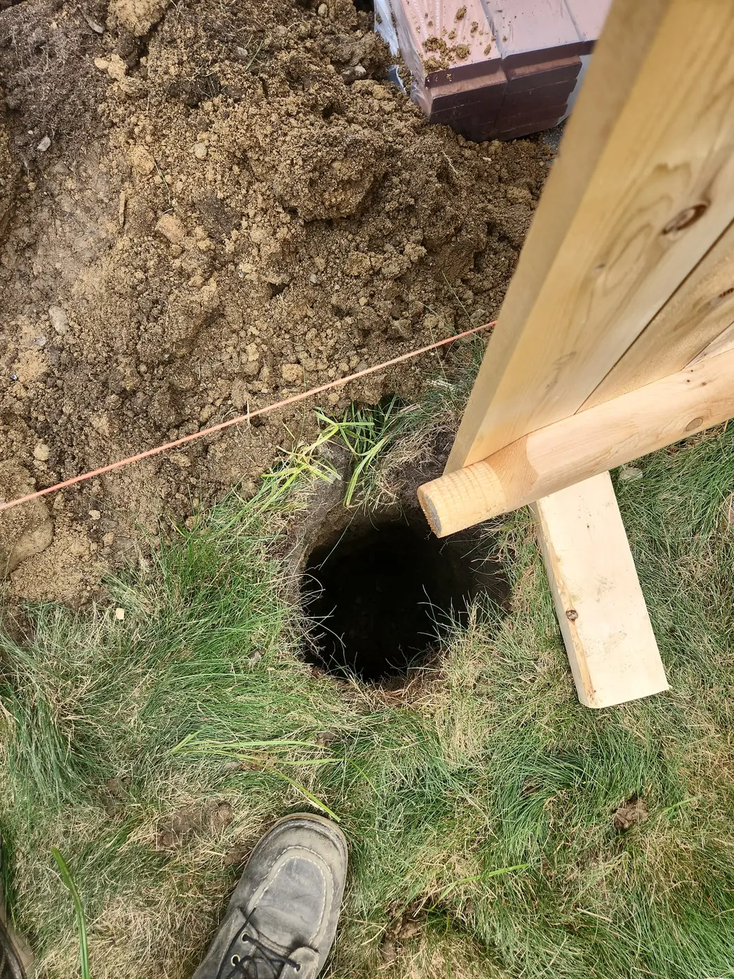 Deep post hole prepared for a cedar privacy fence installation