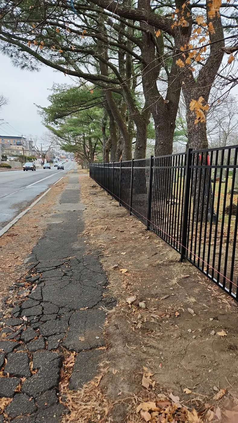 Finished black aluminum fence running beside a sidewalk