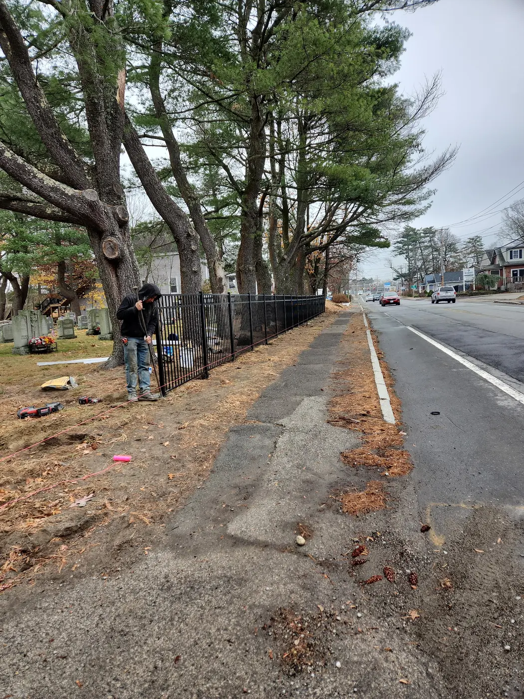 Crew member aligning a long run of black aluminum fencing
