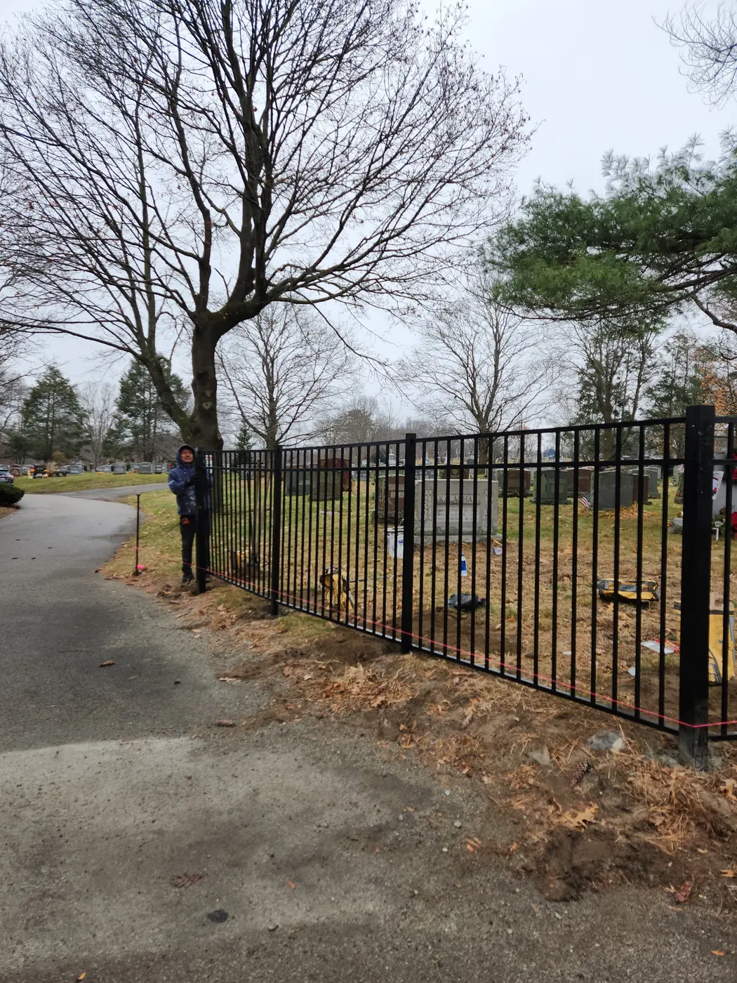 Black aluminum fence panels being installed around a cemetery