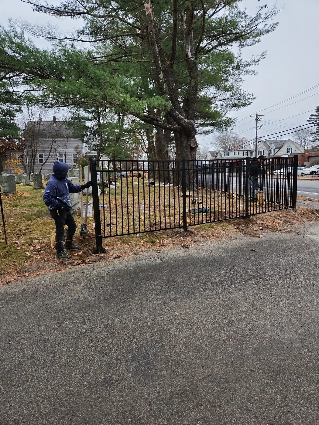 Crew setting black aluminum fence panels at a property corner