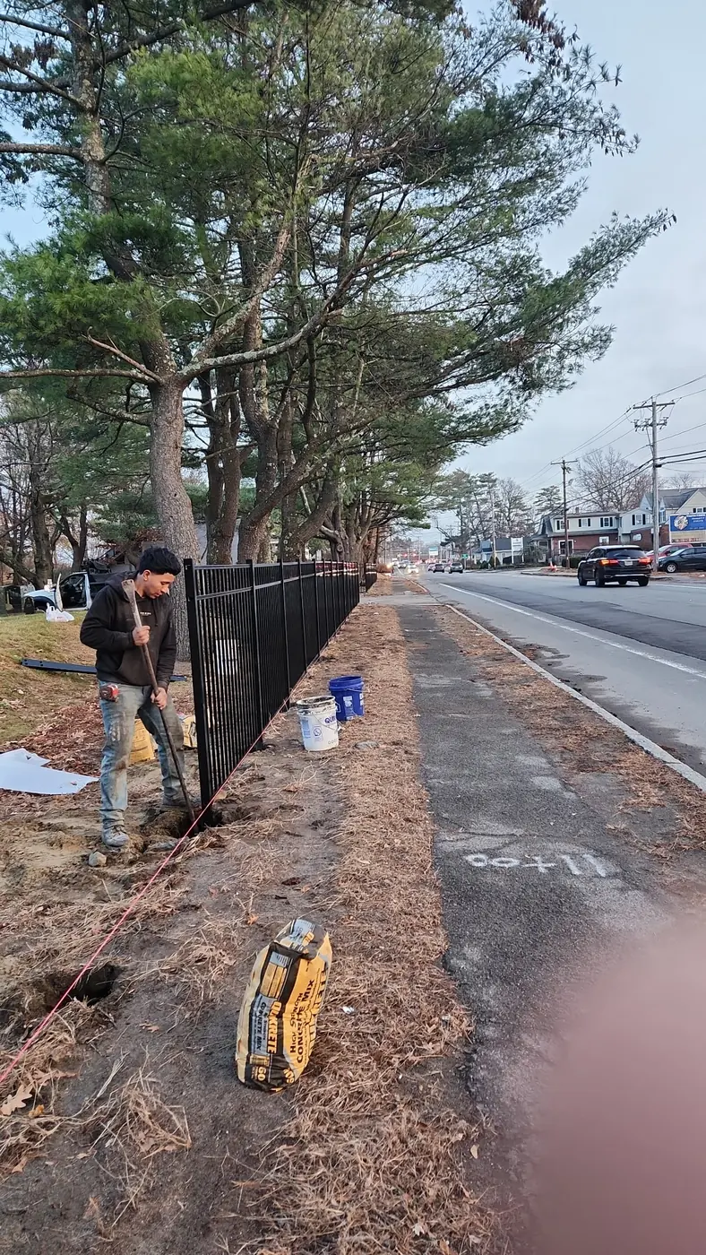 Matul Fence crew member setting a black aluminum fence post