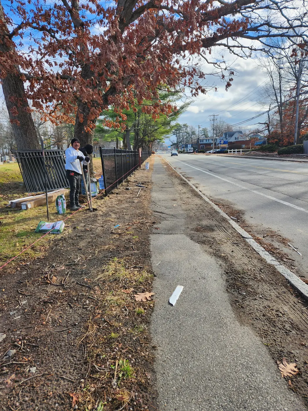 Crew members installing posts for a black aluminum perimeter fence