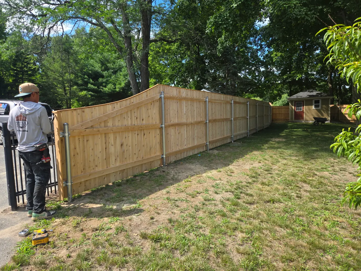 Custom cedar privacy fence meeting a black metal gate