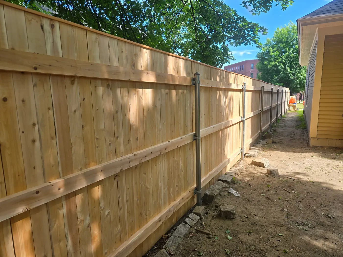 Back side of a new cedar privacy fence supported by metal posts